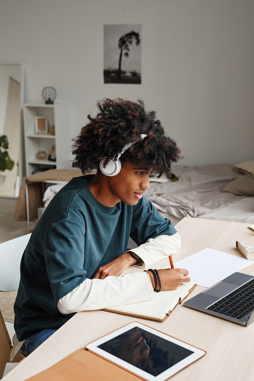 A young man works on his laptop with headphones on